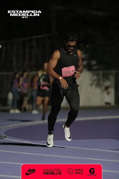 Eros corriendo en una pista atlética de noche, con número de competidor