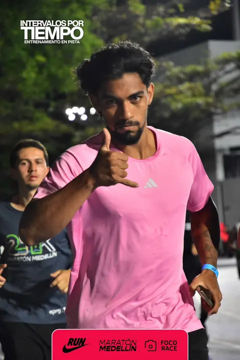 Eros sonriente con camiseta rosada haciendo un saludo con la mano durante un entrenamiento en pista