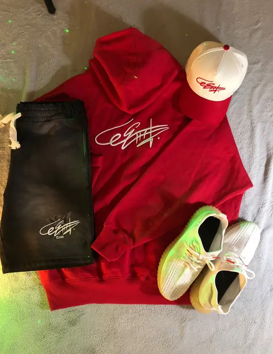 Hoodie rojo con la firma de Eros, pantaloneta negra y gorra crema